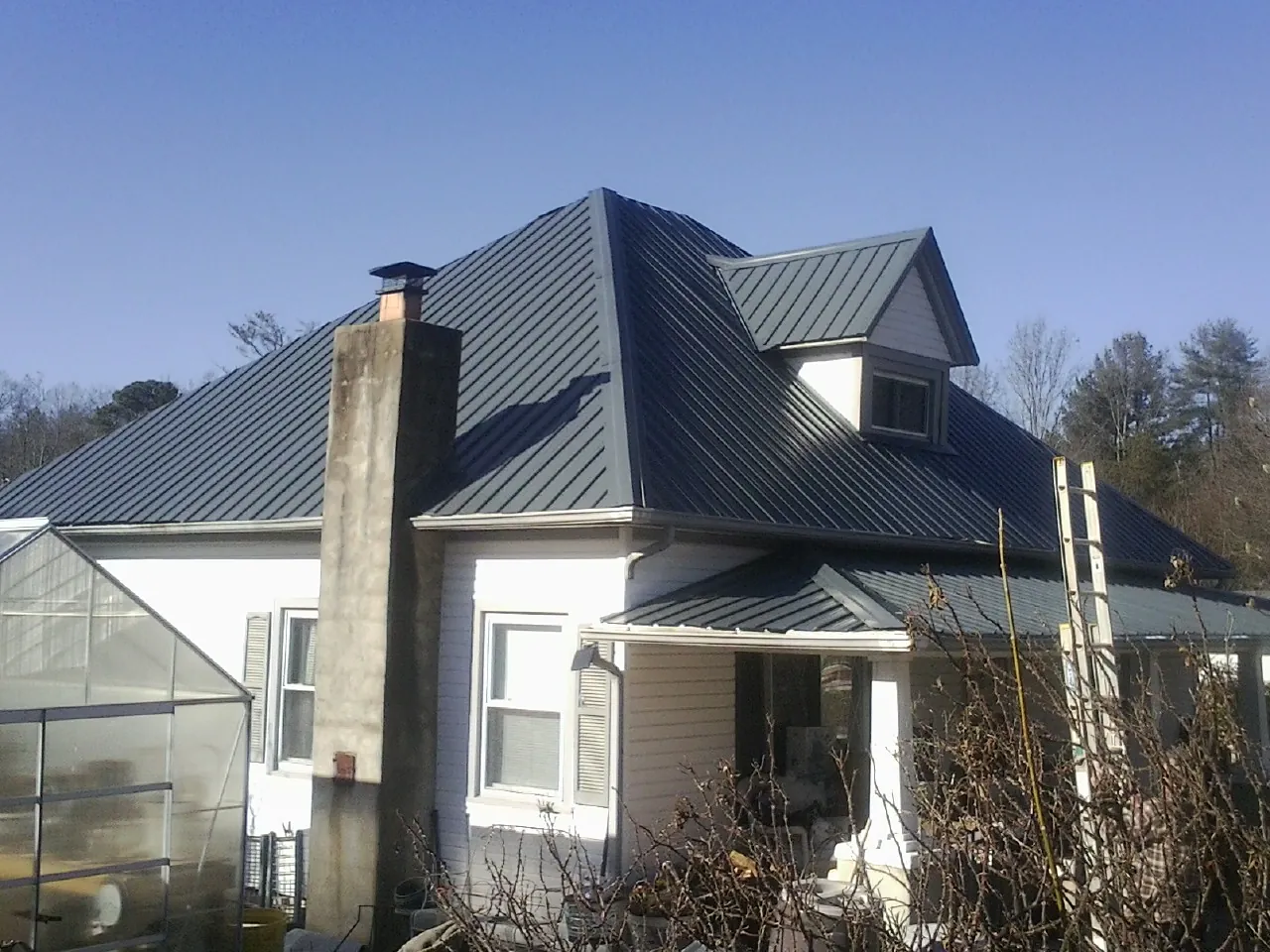 Dark blue standing seam metal roof on a white farmhouse with dormer — Slate & Tile Roof Repair by Roofing Brothers in Tendoy