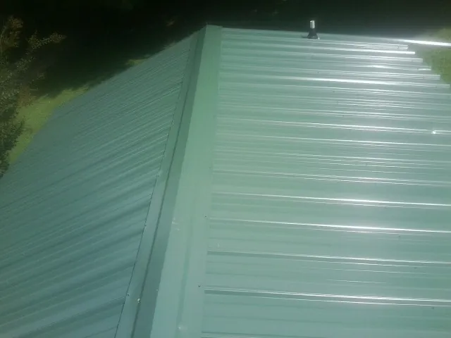 New green metal panels meeting at the ridge of a roof — Flat Roof Repair work by our crew in Tendoy