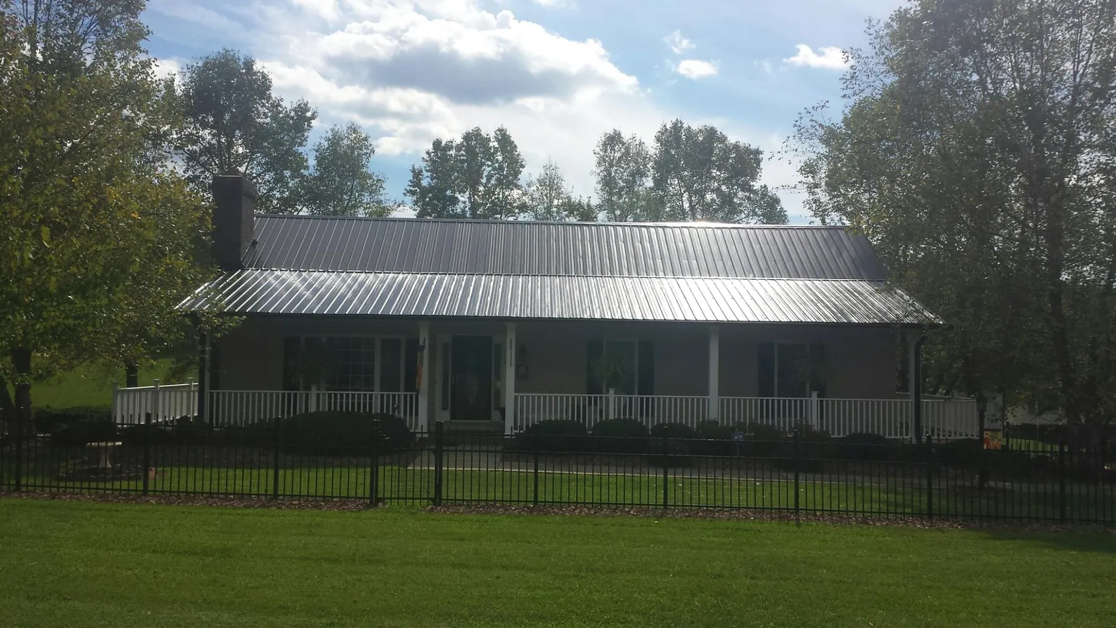 Gray metal roof on a brick ranch with a full width front porch — Gutter Guard Installation work by our crew in Tendoy