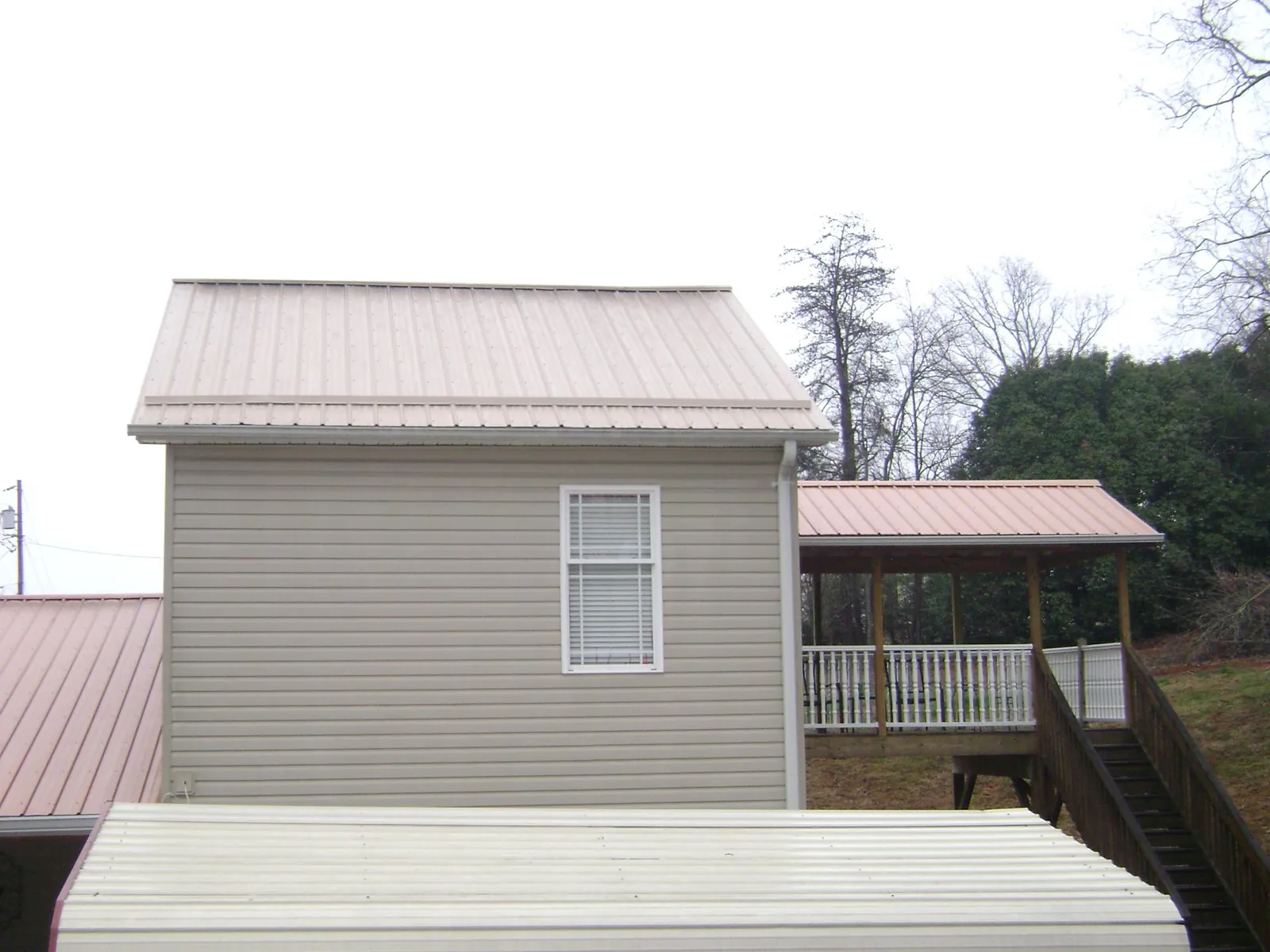 Tan metal roofs on a two story addition and attached porch, from a Roof Replacement job in Tendoy
