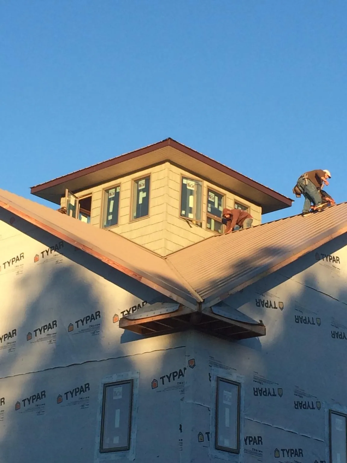 Roofers working around a rooftop cupola on a new metal roof at sunset — Roof Waterproofing in Tendoy by Roofing Brothers